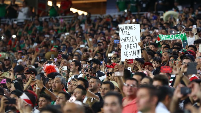 A Mexico fan holds a sign directed at President Donald Trump