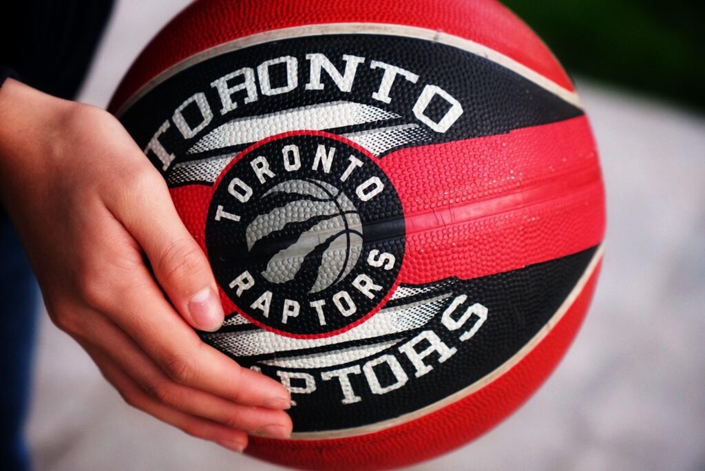 A basketball player stands ready, a Toronto Raptors ball in hand as he practices the sport.