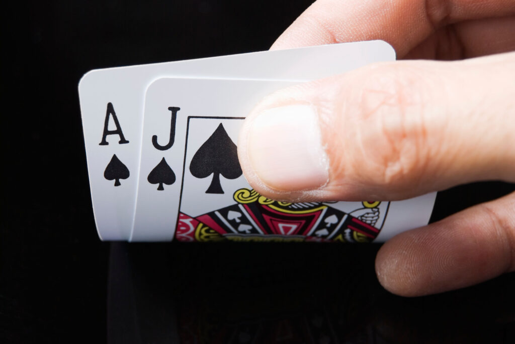 Blackjack cards held by hand against black background